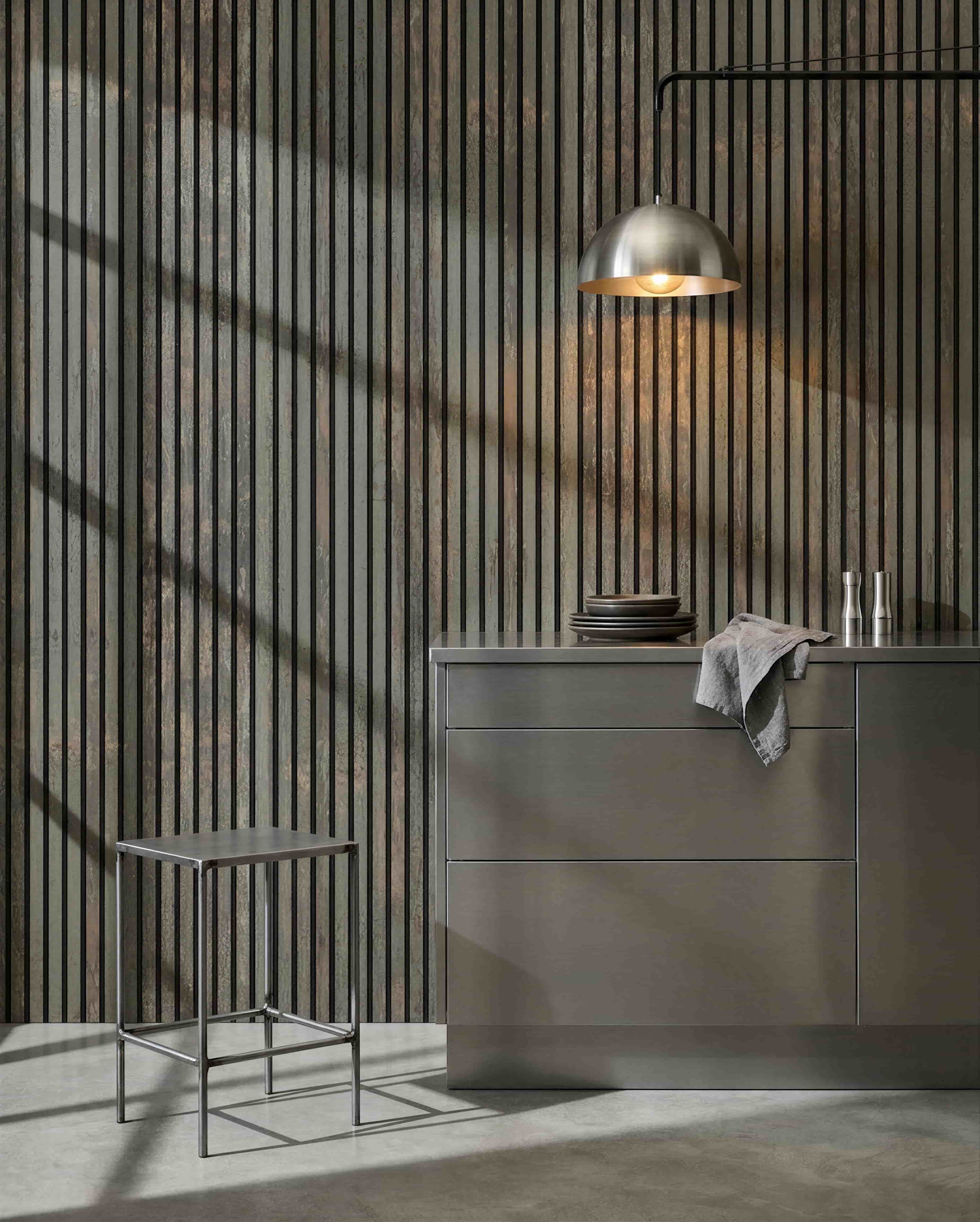 Minimalist kitchen with metal stool, grey island, and dishes, featuring a WoodUpp Akupanel acoustic wood panel in Oxide Grey/Black Felt for sound control.