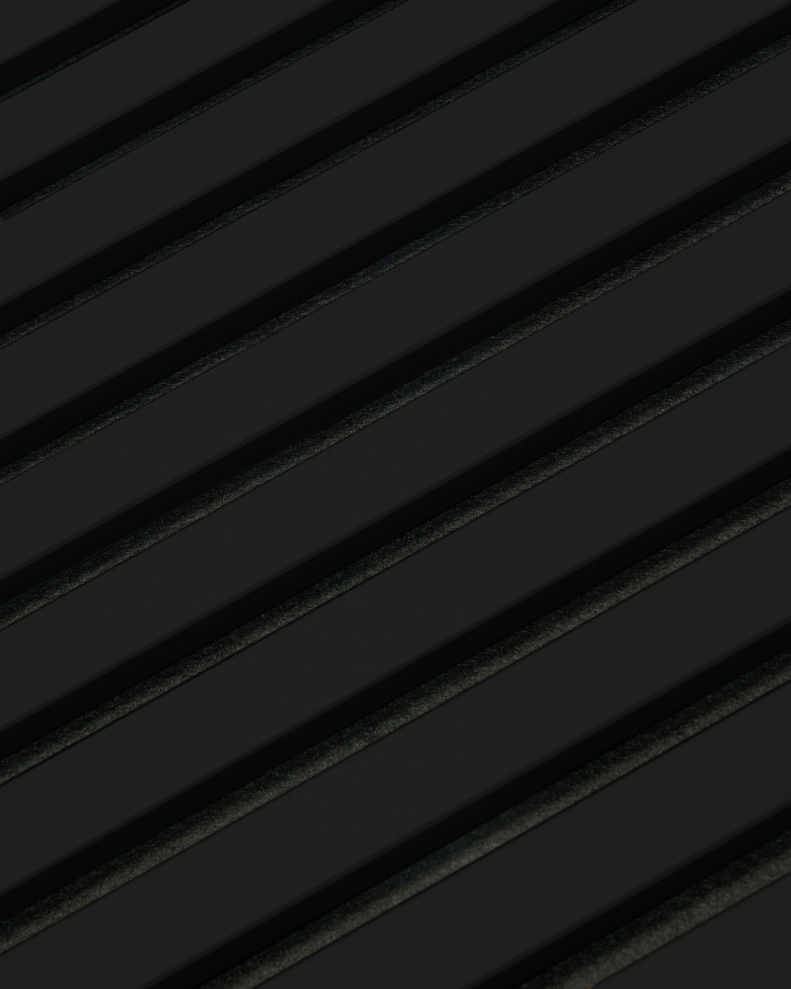 Diagonal black ridges on the WoodUpp Akupanel acoustic panel form a repetitive, industrial pattern across a dark surface, reflecting minimalist Nordic design.