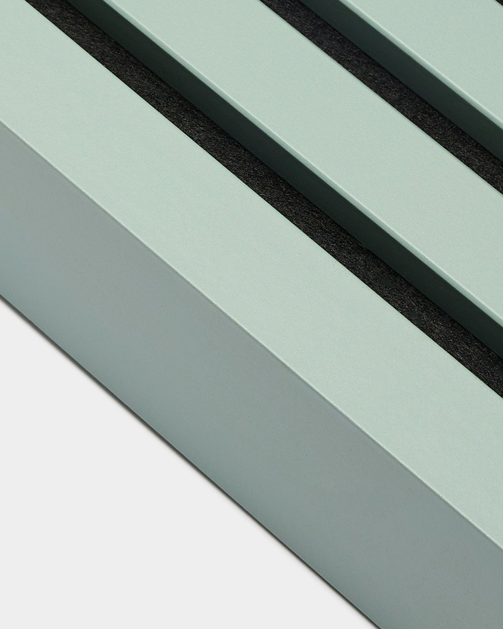 Close-up of WoodUpp Akupanel installation accessory: End lamella in Cloud, 6.7 cm wide, mint green MDF frame with two black grooves on a white background.