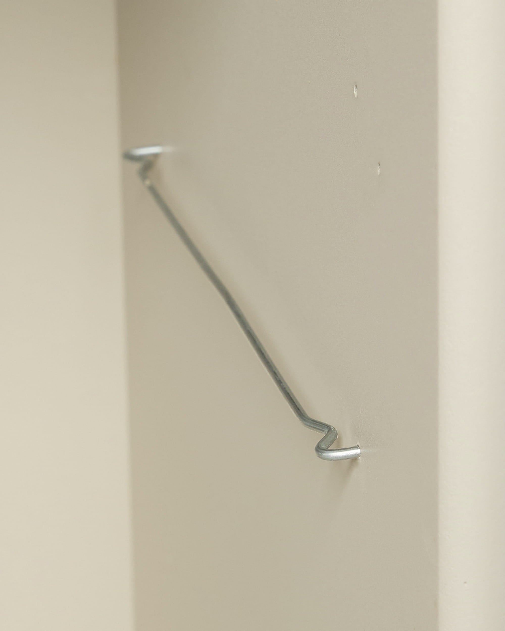 A metal rod with bent ends accents the Arka Bookcase in beige by WoodUpp, reflecting modern Danish design and complementing Nordic acoustic panels.