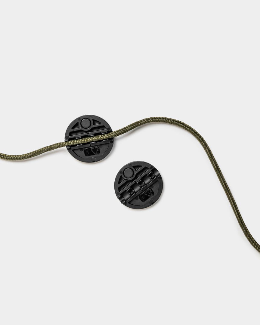 Two WoodUpp Vindar Gallery String cord locks with green braided string, displayed on a plain light gray background.