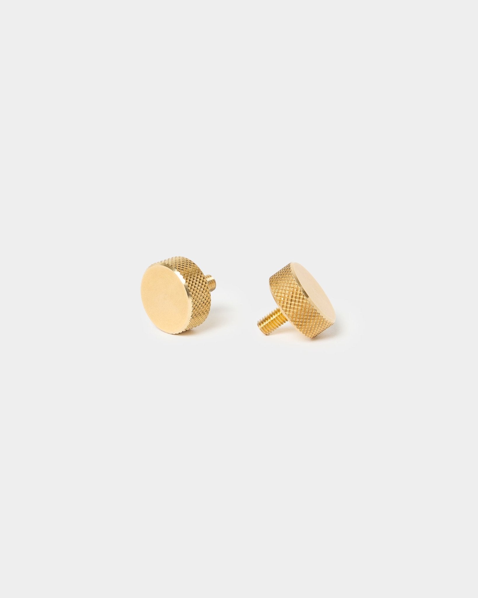 Pair of WoodUpp brass finger screws (M5x10 mm, 20x8.8), with textured edges and short stems, designed for Akupanel accessories, on a plain light background.