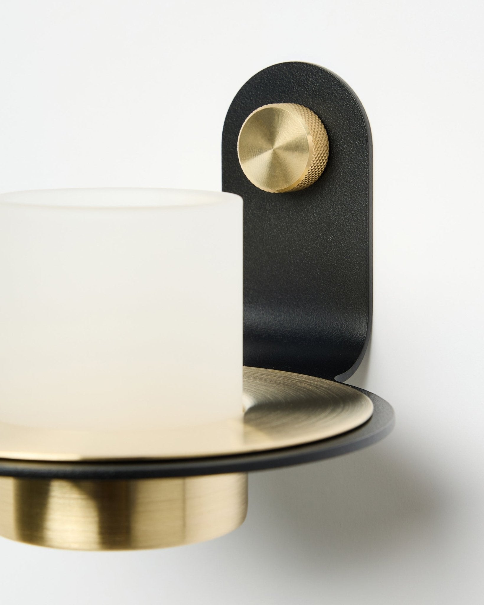 The Norr Candle Holder by WoodUpp, in black and brass, shown mounted with LED candles on a white acoustic panel.