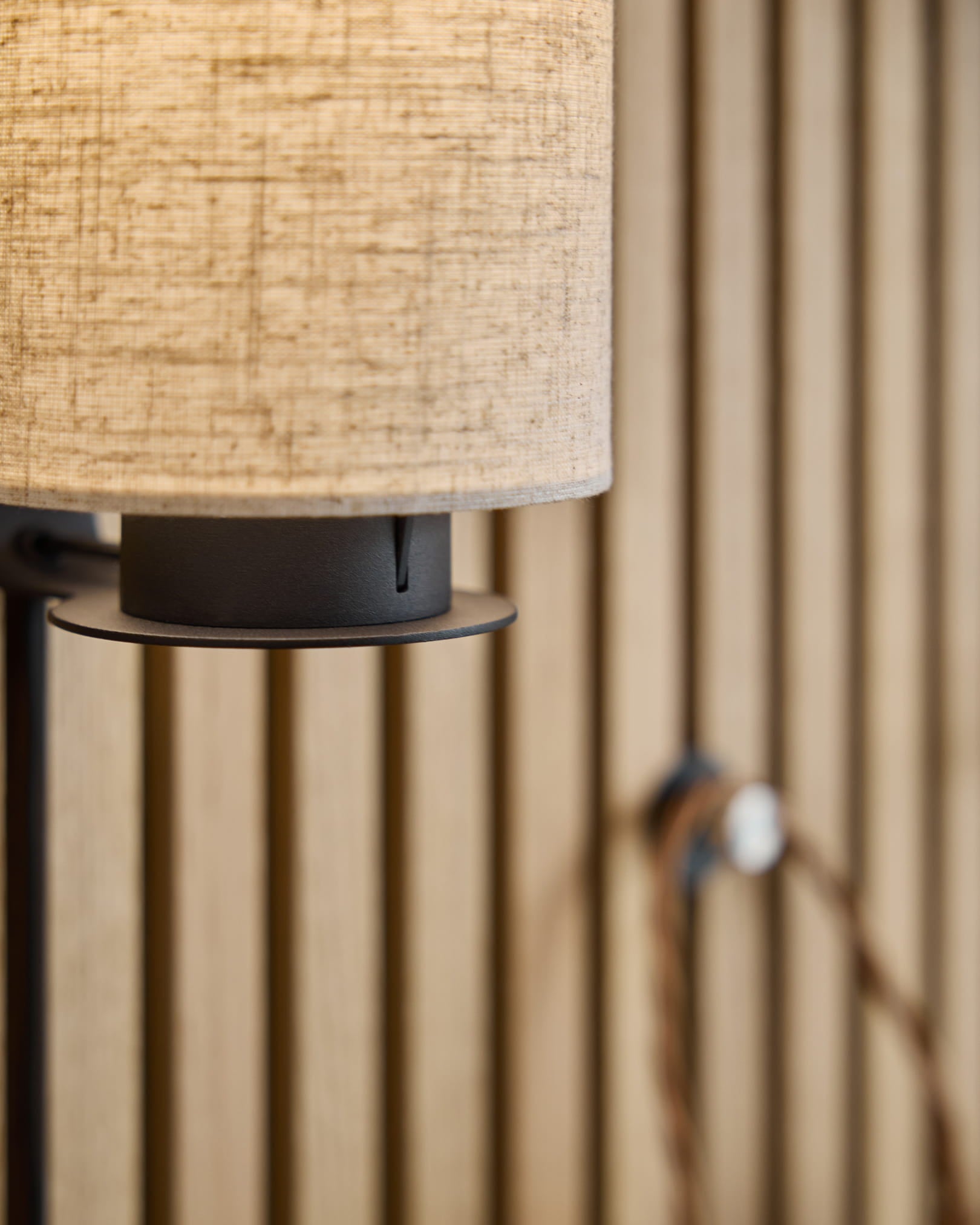 Feya Wall Lamp / Black/Beige by WoodUpp with a beige linen-cotton shade, black metal base, and visible cord mounted on a Nordic acoustic slatwall panel.
