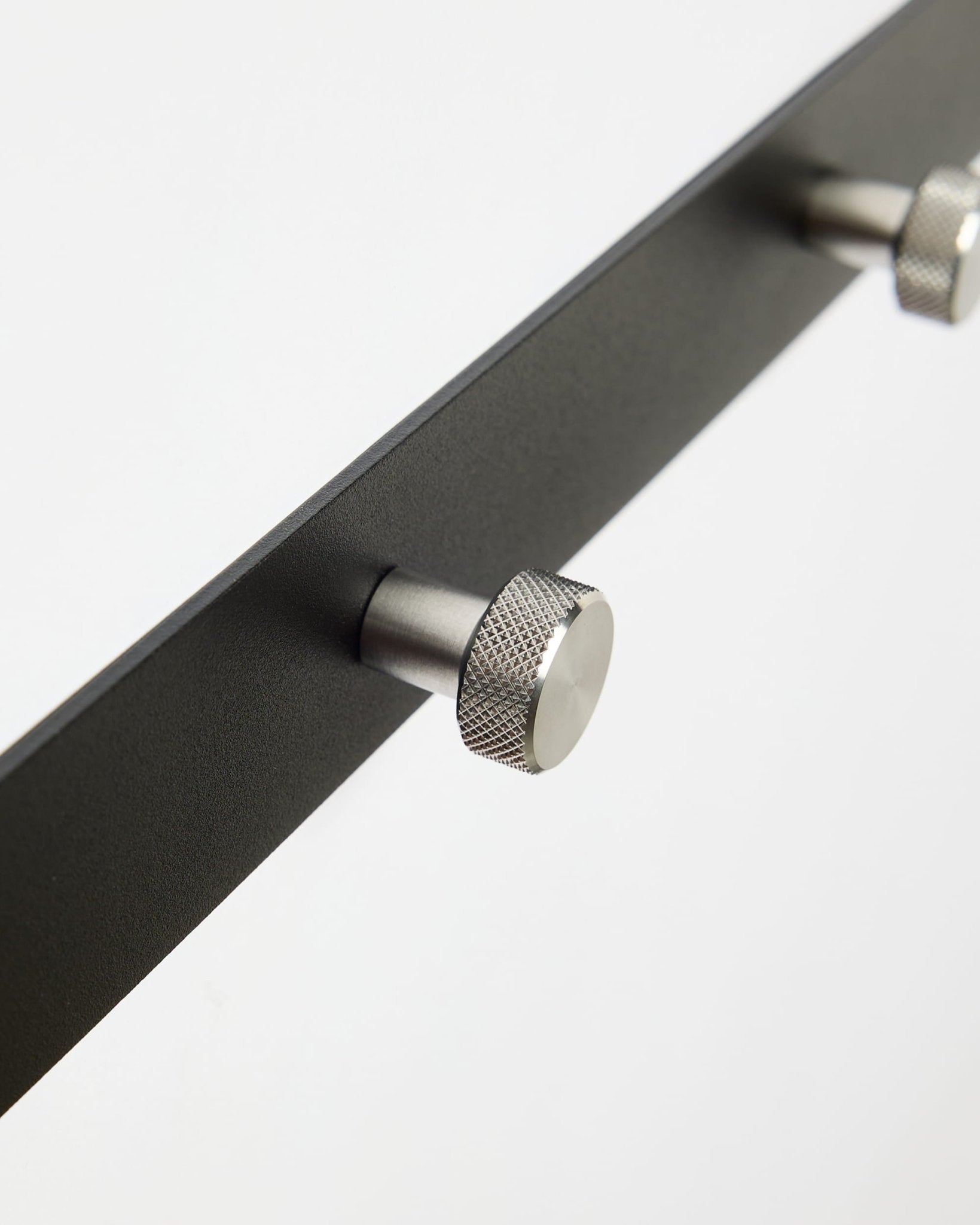 Close-up of Norr | Coat Hook Rack / X5 by WoodUpp in black and stainless steel, designed as an accessory for Akupanel acoustic panels or hallway use.