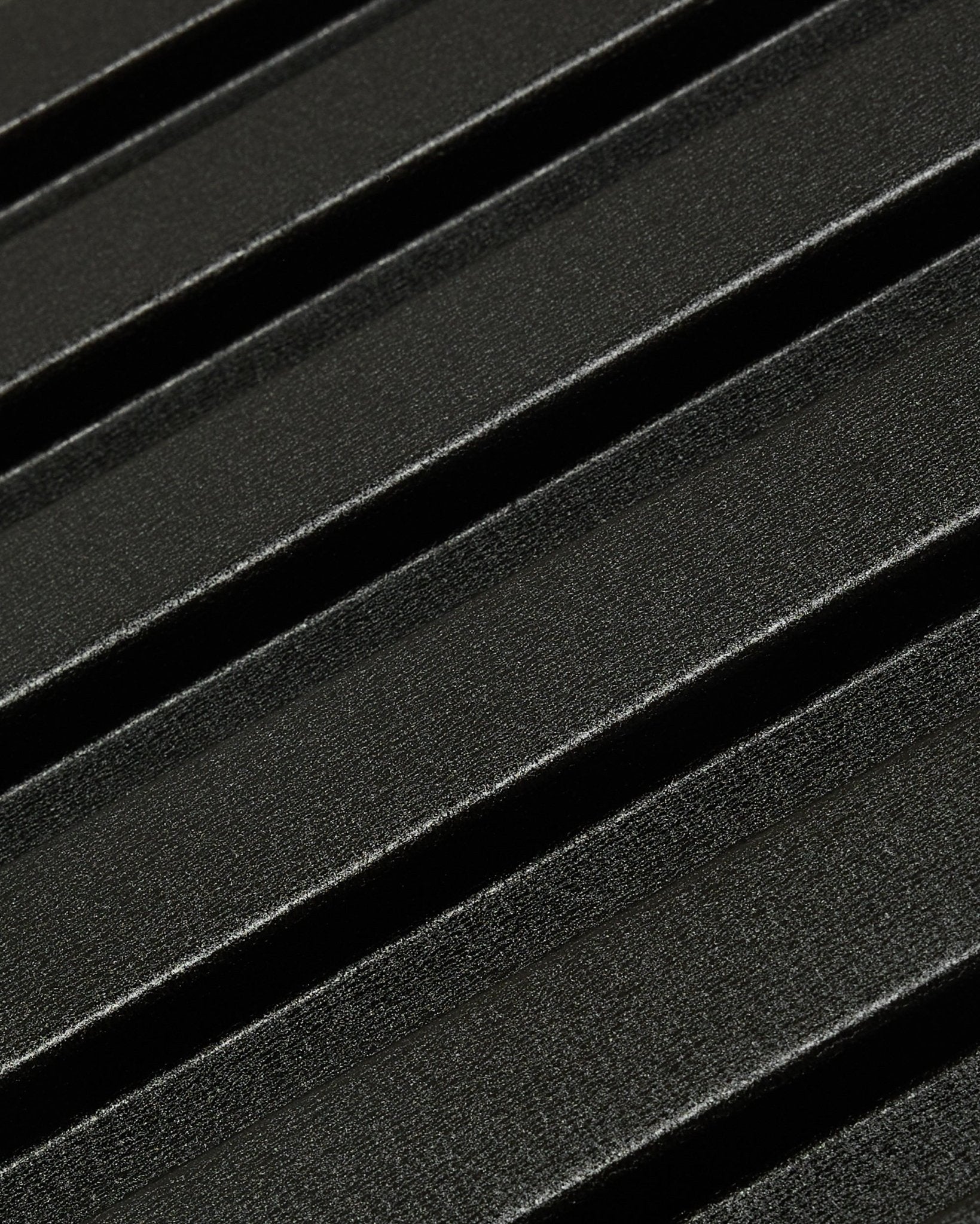 Close-up of Aluwood outdoor facade panel by WoodUpp: dark, textured recycled aluminum surface with diagonal raised ridges, measuring 240 x 45.1 cm.