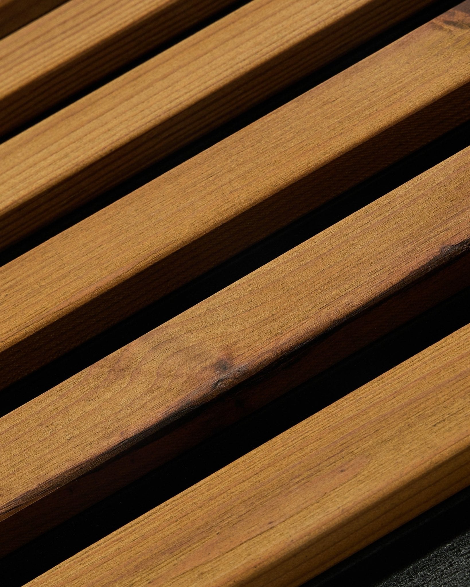 Close-up of WoodUpp Aluwood facade panel in oiled brown (240 x 45.1 cm), thermally treated Nordic spruce, angled to show slats with dark gaps between.