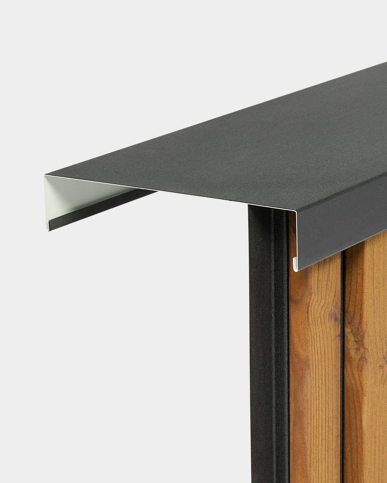 WoodUpp Aluwood Level Wall Capping (240 cm x 20 cm) sits atop a wooden fence, featuring a black powder-coated aluminum profile extending outward.