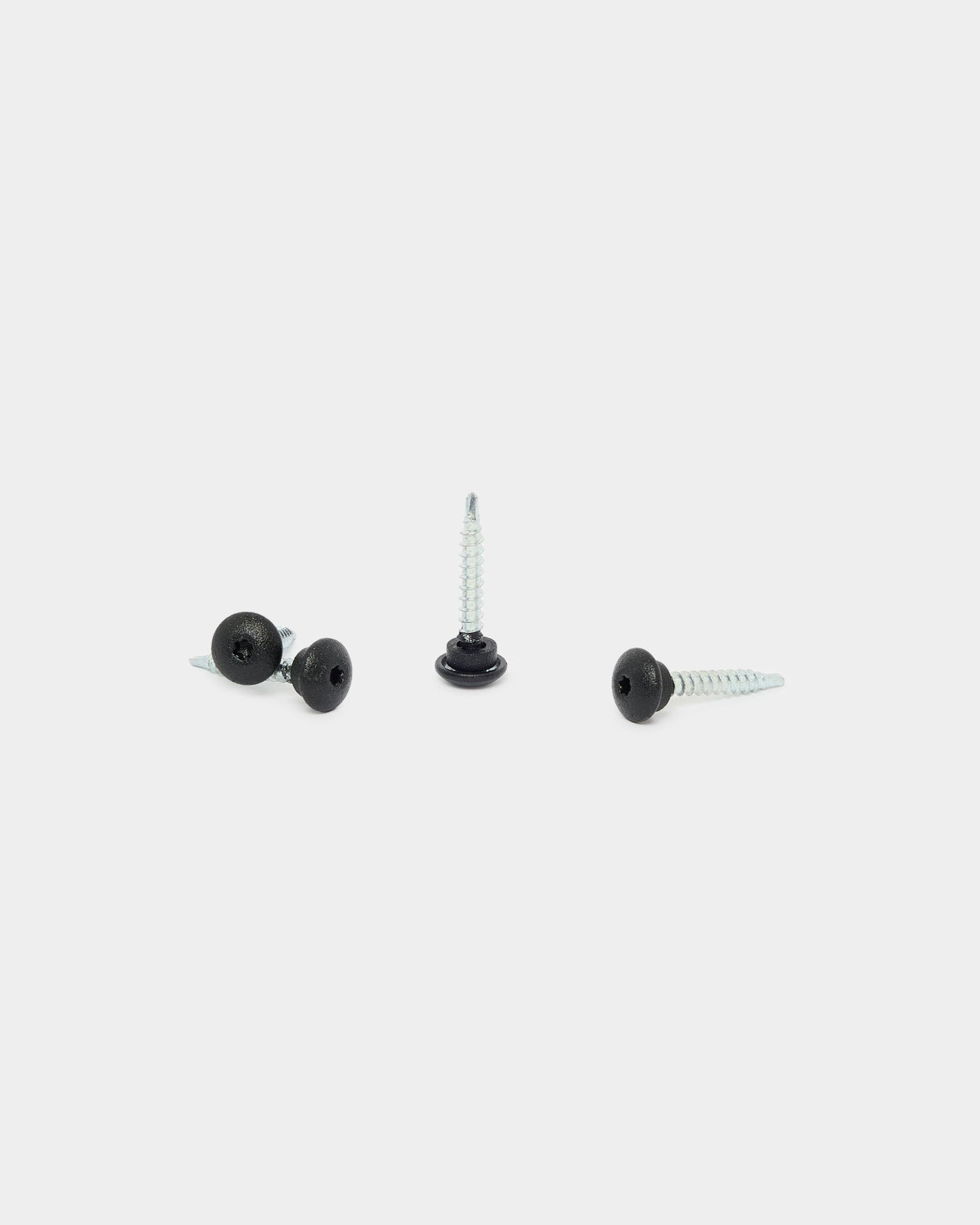 Three WoodUpp black 4.8x35 front screws with Ø9.5 washers, designed for Akupanel acoustic panels, on a white background: one upright, two lying down.