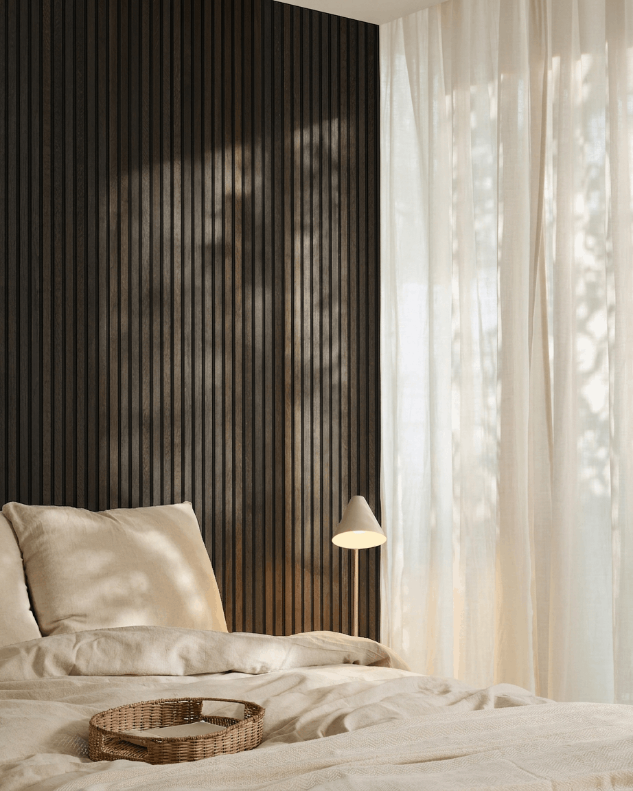 Minimalist bedroom with a beige bed, wicker tray, Scandi accents, and WoodUpp Akupanel acoustic wood panel in Rustic Smoked Oak mounted on a dark wall.